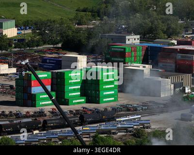 Cincinnati, USA - 19. April 2026: Luftaufnahme von gestapelten Containern und Industrieschienwagen auf einem Logistikhof unter hellem Tageslicht Stockfoto