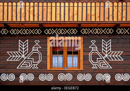 Vor einem Holzhaus mit traditioneller Malerei in der Gemeinde Cicmany in der Slowakei Stockfoto