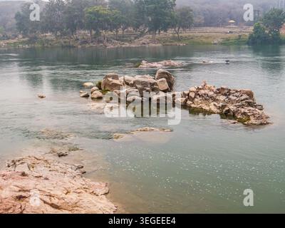 Orchha, Indien, 22.02.20. Ein ruhiger Blick auf den Betwa River mit großen Granitfelsen und nebligen, bewaldeten Ufern in Orchha, Madhya Pradesh. Stockfoto