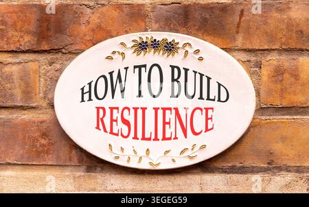 So erstellen Sie ein Resilienzsymbol. Konzeptworte wie man Widerstandsfähigkeit auf einem schönen weißen Schild schafft. Wunderschöner Backsteinmauerhintergrund. Geschäftsanweisungen Stockfoto