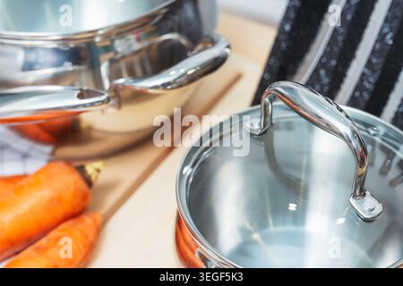 Detaillierte Aufnahme Von Metallic-Töpfen Und Frischen Karotten Mit Glänzenden Reflexen In Moderner Küche Stockfoto