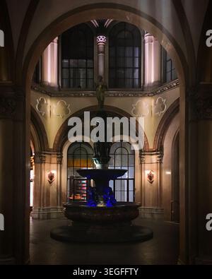 Verziertes Inneres eines Gebäudes in Wien, Österreich mit einem eleganten Brunnen als Mittelpunkt. Der Brunnen zeigt eine klassische Statue auf der Spitze, sur Stockfoto