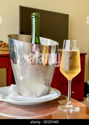 Flöte Glas gekühlten Champagner und eine Flasche in einem Eiskübel im Schlafzimmer eines Luxushotels. Keine Personen. Stockfoto