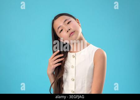Eine hübsche junge asiatische Frau, die aufblickt und den Kopf geneigt träumt Stockfoto