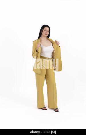 Elegante Geschäftsfrau steht und posiert in modernem, stilvollem Hosenanzug drinnen Stockfoto