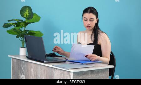 Konzentrierte Geschäftsfrau, die Berichte am Schreibtisch liest Stockfoto