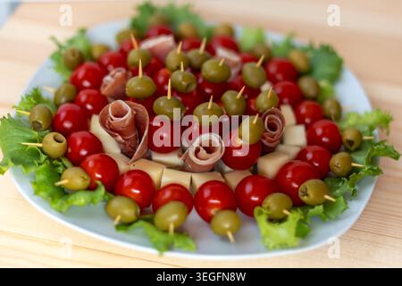 Eine köstliche Party-Vorspeiseplatte mit bunten Spießen mit Reifen Kirschtomaten, grünen Oliven, Käsewürfeln und gerolltem Schinken Stockfoto