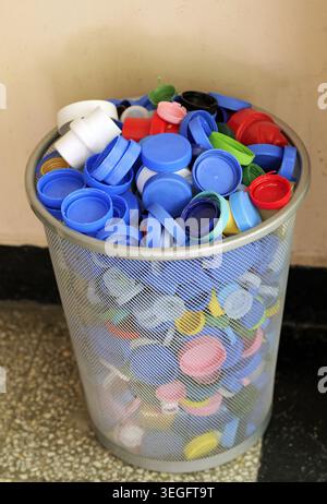 Abfalleimer aus Mesh, die bis oben mit einer Auswahl an bunten Plastikverschlüssen gefüllt sind, sammeln sie für ein ordnungsgemäßes Recycling und fördern eine Kreislaufwirtschaft Stockfoto