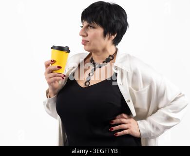 Selbstbewusste reife Frau, die eine Kaffeetasse hält und in die Kamera schaut Stockfoto
