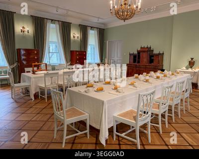 Eleganter Speisesaal mit weißen Tischdecken, Holzmöbeln und dekorativen Elementen in einem historischen Innenraum Stockfoto