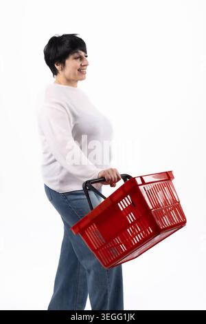 Glückliche Frau mittleren Alters, die einen roten Einkaufskorb hält Stockfoto