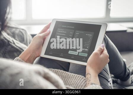 Nahaufnahme einer Frau, die ein Tablet in der Hand hält, mit Bestellbestätigungsschnittstelle auf dem Bildschirm zu Hause. Konzept von Online-Shopping, E-Commerce, erfolgreichem Kauf, digi Stockfoto