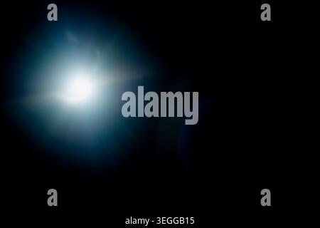 Helle Linsenreflexion mit optischer Blendwirkung und Starburst-Effekt auf Schwarz Stockfoto