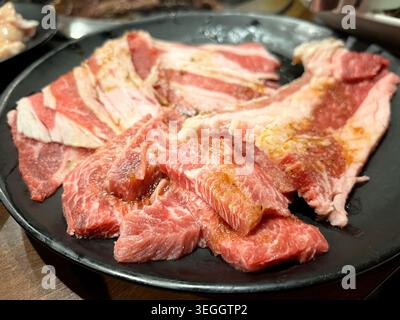 Erstklassige, rohe Wagyu-Rindfleischscheiben mit wunderschöner Marmorierung auf einer schwarzen Platte. Stockfoto