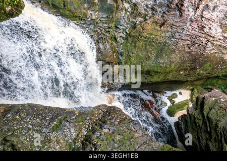 Rauschendes Wasser stürzt über zerklüftete Steinformationen, umgeben von üppigem Grün am Las Delicias Wasserfall in Guaviare, Kolumbien. Stockfoto
