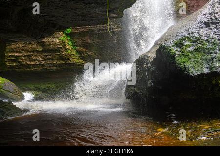 Ein Wasserfall fließt energetisch über moosige Felsbrocken und erzeugt einen nebeligen Sprühnebel vor einer natürlichen Felsenkulisse in Kolumbien. Stockfoto