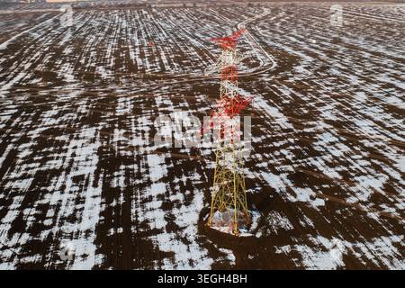 Drohnenansicht des Stromübertragungsnetzes in der Winterlandschaft, beleuchtet durch Sonnenuntergangslicht. Stockfoto