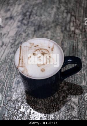 Cat Face Coffee Art gedruckt auf Latte Foam in Dunkelblau Becher auf rustikaler Vintage Oberfläche Hochwinkel Ansicht Stockfoto
