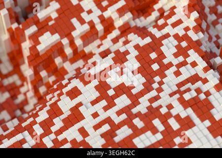 Horizontale 3D-Abbildung von oben, die eine rote und weiße Voxelmosaikfläche mit gepixelter geometrischer Textur zeigt. Stockfoto