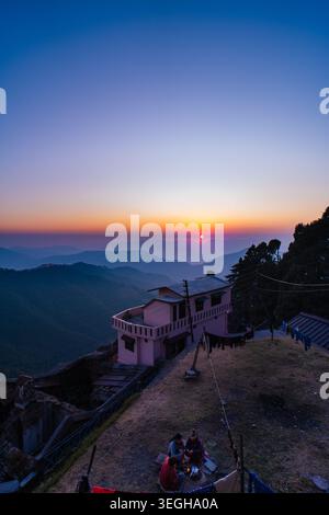 Ein friedliches Berghaus auf einer Klippe während eines farbenfrohen Sonnenuntergangs mit Panoramablick auf das Tal in Chakrata, Uttarakhand, Indien. Stockfoto