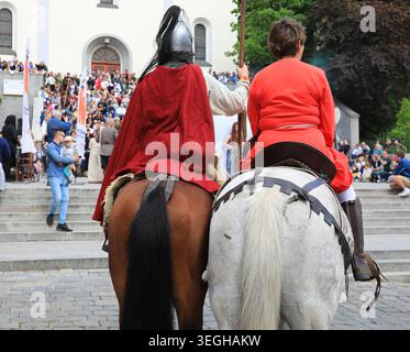 Historisches oder traditionelles Ereignis, Rückansicht eines weißen Pferdes, das von einer Person in rotem Gewand geritten wird, der Reiter des braunen Pferdes ist mit einem Met gekleidet Stockfoto