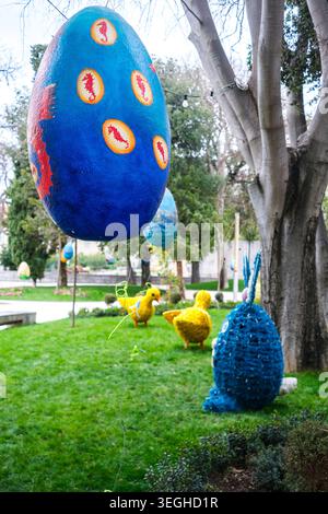 Große bunte Ostereier und bezaubernde Küken- und Hasenfiguren sorgen für eine herrliche Outdoor-Präsentation auf üppig grünem Gras in einem Park. Stockfoto