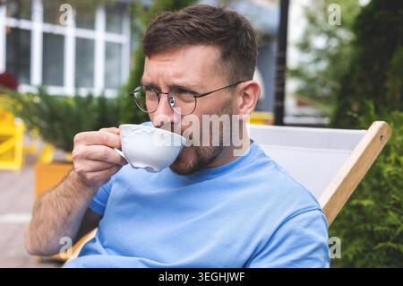 Ein junger Mann trinkt Morgenkaffee auf einer Terrasse Stockfoto