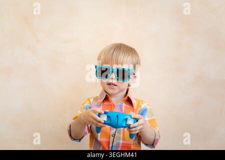 Gamer Kind spielt zu Hause Videospiele. Porträt eines lustigen Kindes mit Joystick Stockfoto