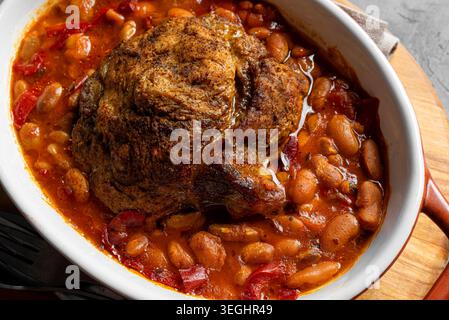 Langsam kochendes Schweinefleisch und weiße Bohnen aus nächster Nähe. Im Ofen gebackenes zartes Schweinefleisch und Kidneybohnen in reichhaltiger Gemüsesauce, deftige Mahlzeit für den Herbst und Stockfoto