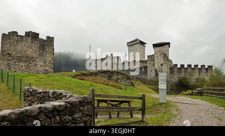 Ossana, Italien - 20.05.2026: Die alten Steinbefestigungen der Burg San Michele (Castlo di San Michele) stehen auf einem grasbewachsenen Hügel in Ossan Stockfoto