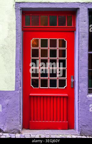 Rote Holztür in einem alten, weißen Gebäude in Flieder Stockfoto