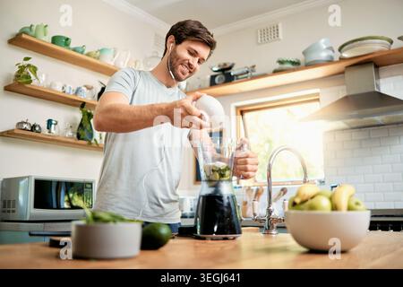 Kopfhörer, Mann und Joghurt im Mixer zu Hause für grünen Smoothie, gesunde Ernährung oder Detox Shake. Musik, fröhliche Person oder Zubereitung von Mahlzeiten mit Zutaten in Stockfoto