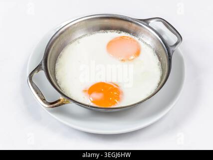 Gebratene Eier zum Servieren in einer Pfanne, frische Sunny-Side-Up-Eier mit goldenen Eigelb, zubereitet für das Frühstück und traditionelle Hausmannskost Stockfoto