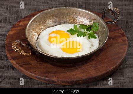 Gebratene Eier zum Servieren in einer Pfanne, frische Sunny-Side-Up-Eier mit goldenen Eigelb, zubereitet für das Frühstück und traditionelle Hausmannskost Stockfoto