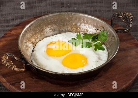 Gebratene Eier zum Servieren in einer Pfanne, frische Sunny-Side-Up-Eier mit goldenen Eigelb, zubereitet für das Frühstück und traditionelle Hausmannskost Stockfoto