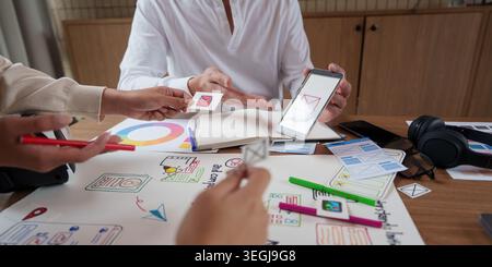 Asiatische UX-UI-Designer arbeiten an der Entwicklung mobiler Anwendungsschnittstellen im Büro zusammen. Stockfoto