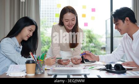 Asiatische UX-UI-Designer arbeiten an der Entwicklung mobiler Anwendungen in modernen Büros zusammen. Stockfoto