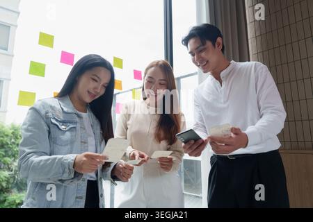 Asiatische UX-UI-Designer arbeiten an der Entwicklung mobiler Anwendungen im Büro zusammen. Stockfoto
