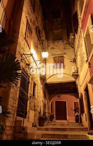 Enge Steingasse mit Stufen und Bogengang in der Altstadt von Rovinj, Kroatien, beleuchtet bei Nacht. Stockfoto
