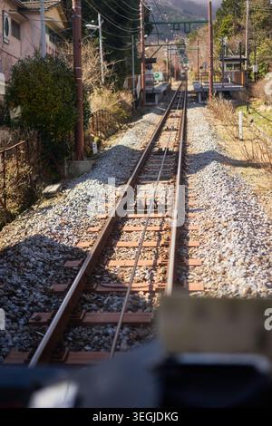 Eine friedliche Reise durch Hakone, Japan, mit dem historischen orangen Bergzug, der steile Strecken fährt und Seilbahnen in dicken Zügen verschwindet Stockfoto