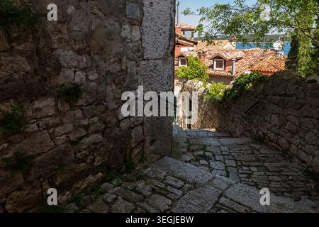 Enge Steinallee in der Altstadt von Rovinj, Kroatien, mit Terrakotta-Dachhäusern und Blick auf das Wasser. Stockfoto