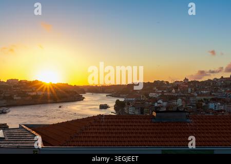 Erhöhter Blick auf den Fluss Douro bei Sonnenuntergang von Porto aus, mit einem dramatischen Sonnenstern, der über dem Horizont platzt, der Fluss reflektiert goldenes Licht, Möwen Stockfoto