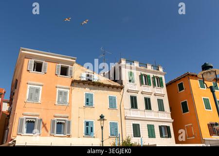 Eine Reihe farbenfroher mehrstöckiger Gebäude mit Fensterläden in der Altstadt von Rovinj, Kroatien unter einem klaren blauen Himmel. Stockfoto