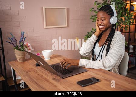 Junge Erwachsene Frau, die Musik genießt, während sie von zu Hause aus arbeitet Stockfoto