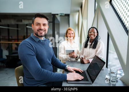 Vielseitiges Geschäftsteam, das im Büro mit Laptop und Tablet zusammenarbeitet Stockfoto