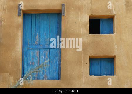 Eine geschlossene Holztür mit abblätternder Farbe und zwei kleinen Fenstern. Stockfoto