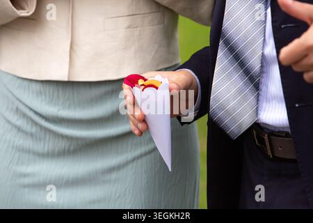 Mann im Anzug, der Papierkegel mit bunten Blütenblättern für Hochzeitkonfetti-Wurf hält Stockfoto