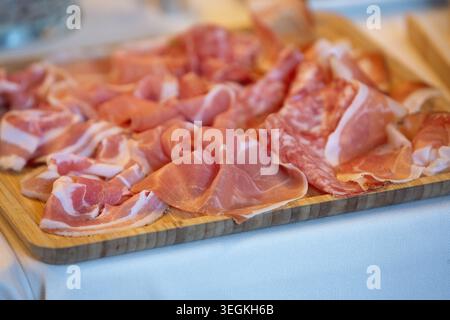 Verschiedene aufgeschnittene Wurstwaren einschließlich Schinken, Pancetta und Salami auf einem Holzbrett Stockfoto