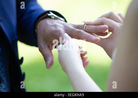 Nahaufnahme der Hände der Braut, die während der Zeremonie einen Ehering auf den Finger des Bräutigams gelegt hat Stockfoto