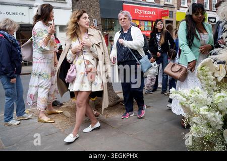 Andere Fußgänger und Käufer kommen an einer Reihe von Bewunderern einer thematischen Blumenausstellung vorbei und kaufen an der Kings Road während des zweiten Tages der Chelsea Flower Show am 20. Mai 2026 in London, England. „Chelsea in Bloom“ ist ein kostenloses Straßenfest mit frischen Blumen vor den Händlern von Chelsea und wird von Cadogan in Zusammenarbeit mit der Royal Horticultural Society (RHS) produziert, die ab dem 18-24. Mai die Straßen von Chelsea umgestaltet. Der jährliche Wettbewerb ist für 145 Unternehmen von Chelsea, die ihre Außenbereiche mit kreativen Designs bekleiden und um die begehrten Auszeichnungen konkurrieren Stockfoto